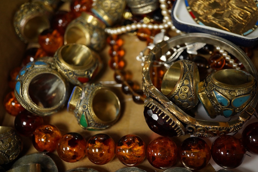 A collection of costume jewels, comprising: an Egyptian-style oval medallion pendant bordered in enamel; two imitation amber necklaces; a simulant pearl necklace; a pair of floral drop earrings; five lapis rings; a bangl